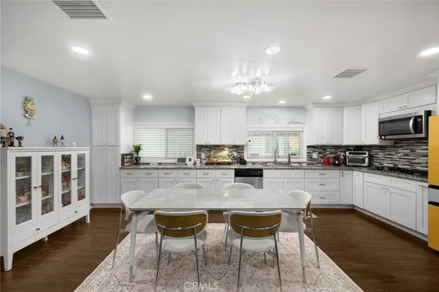 a kitchen with stainless steel appliances granite countertop a stove top oven a sink a dining table and chairs