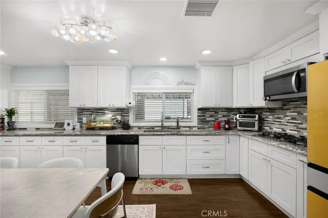 a kitchen with granite countertop a stove sink microwave and cabinets