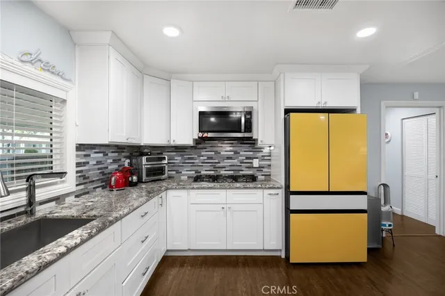 a kitchen with stainless steel appliances granite countertop a stove a sink and a microwave