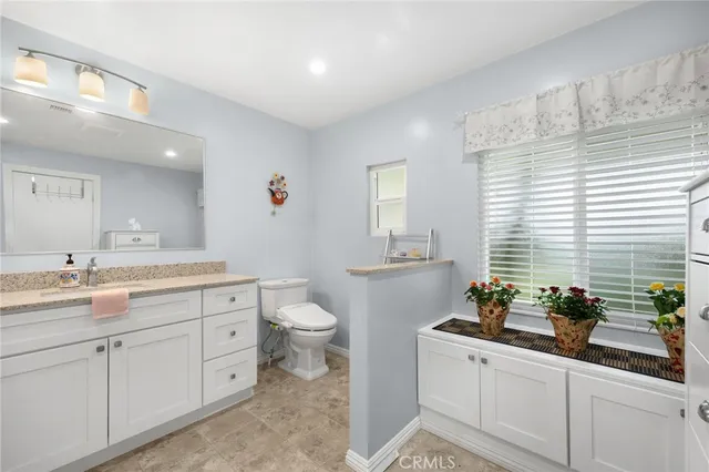 a spacious bathroom with a granite countertop sink a toilet and a window