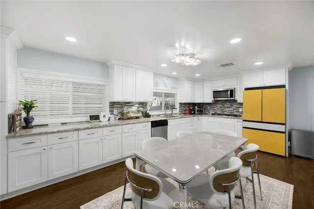 a kitchen with stainless steel appliances granite countertop a table chairs sink refrigerator and microwave