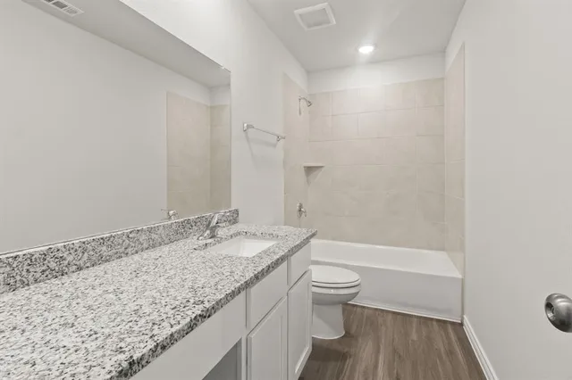 a bathroom with a granite countertop sink a toilet and bathtub