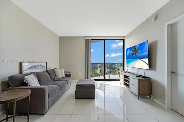 a living room with furniture a flat screen tv and a floor to ceiling window