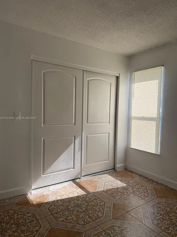 a view of an empty room with window and closet area