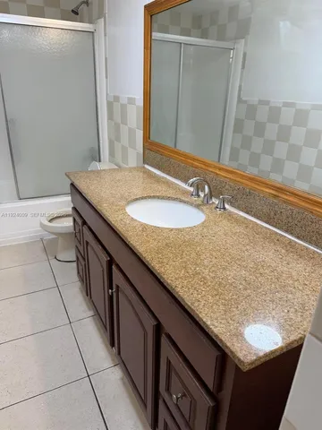a bathroom with a granite countertop sink and a mirror