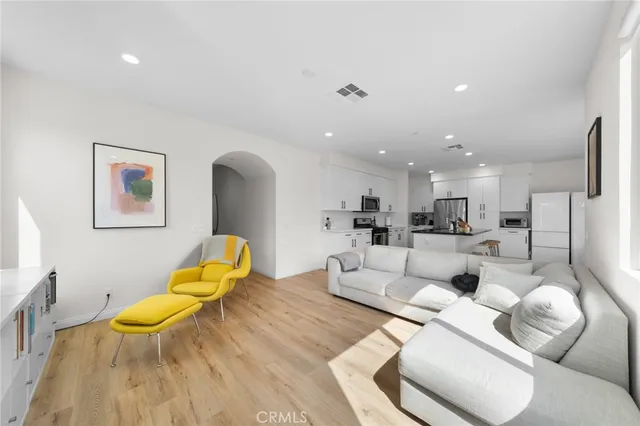 a living room with furniture kitchen view and a wooden floor