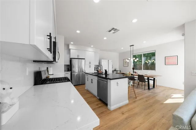 a kitchen with stainless steel appliances a sink a stove a refrigerator cabinets and living room view