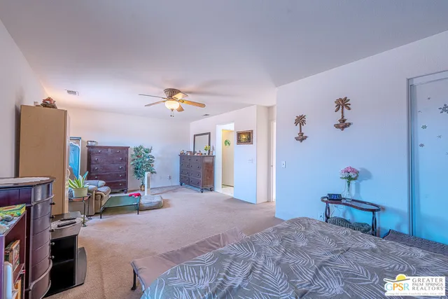 a bedroom with a bed desk and a flat tv screen
