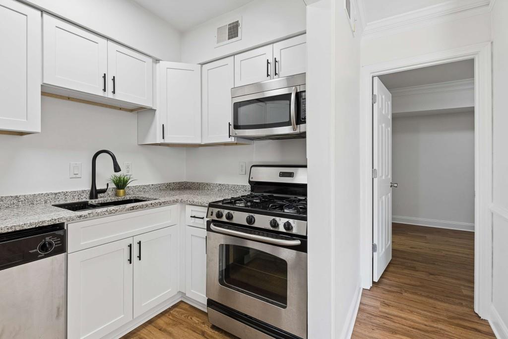 6980 Roswell Road, Unit C13 Atlanta, GA 30328 - Photo 19 of 49 a kitchen with cabinets stainless steel appliances and wooden floor