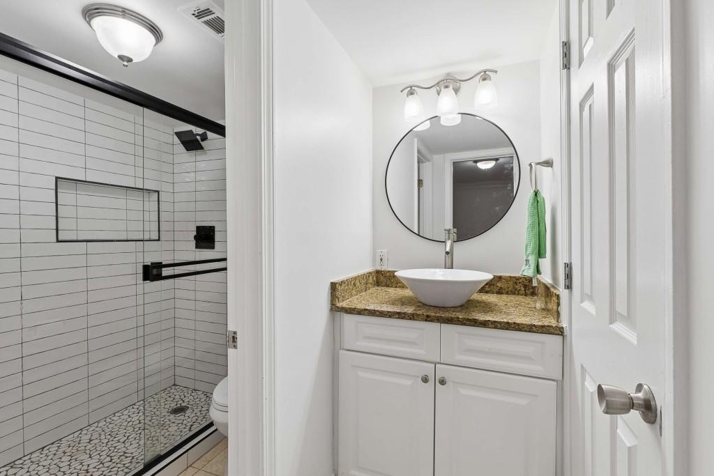 6980 Roswell Road, Unit C13 Atlanta, GA 30328 - Photo 33 of 49 a bathroom with a granite countertop sink a mirror and shower