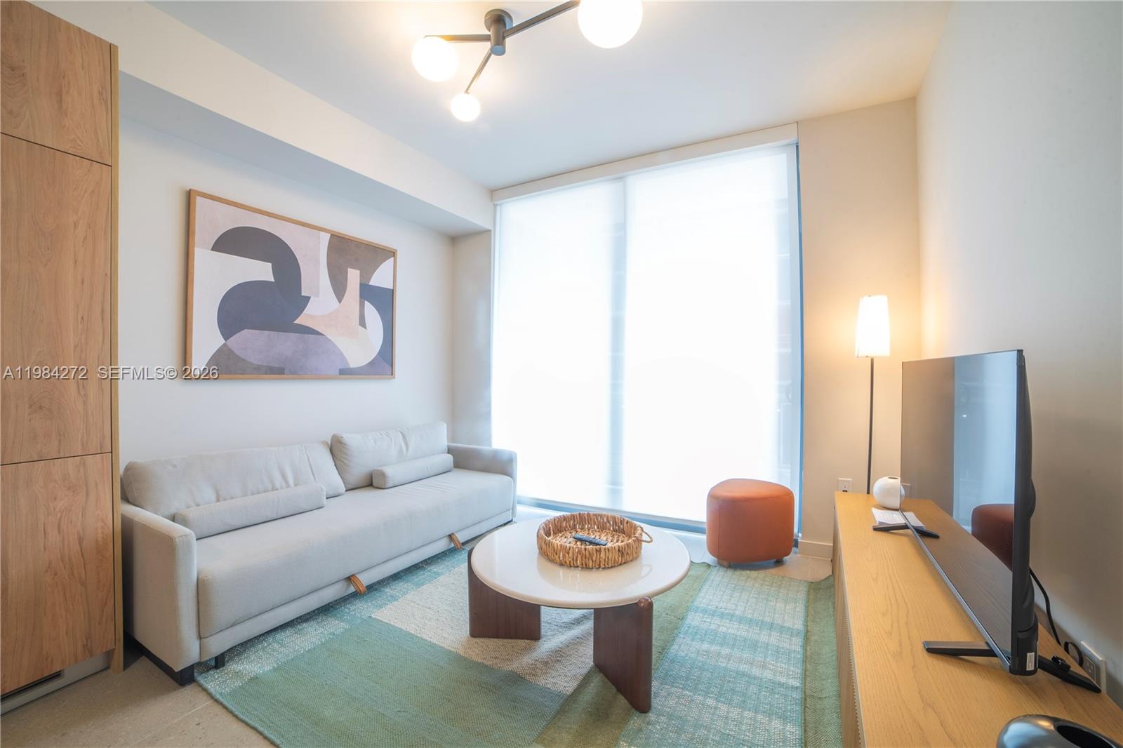 11 Northeast 6th Street, Unit 1403 Miami, FL 33132 - Photo 6 of 44 a living room with furniture and a flat screen tv