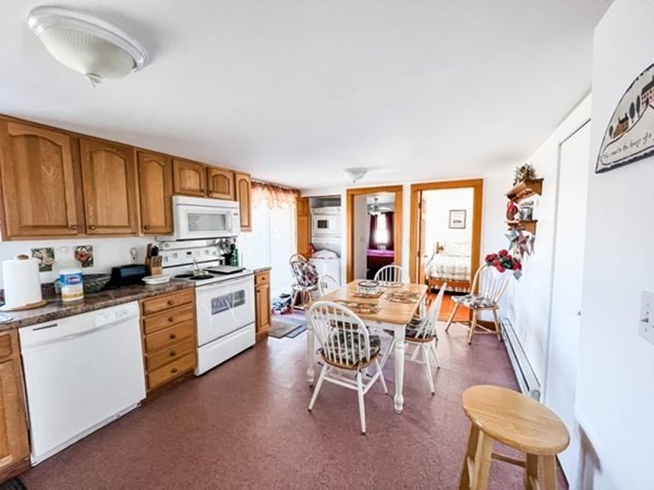 849 State Road, Unit 1 Aquinnah, MA 02535 - Photo 3 of 8 a kitchen with a table chairs refrigerator and cabinets