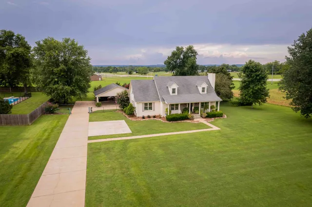 a aerial view of a house with swimming pool in front of big yard