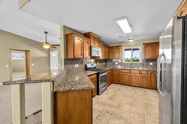 a kitchen with stainless steel appliances granite countertop a stove top oven a refrigerator and a granite counter tops with white cabinets