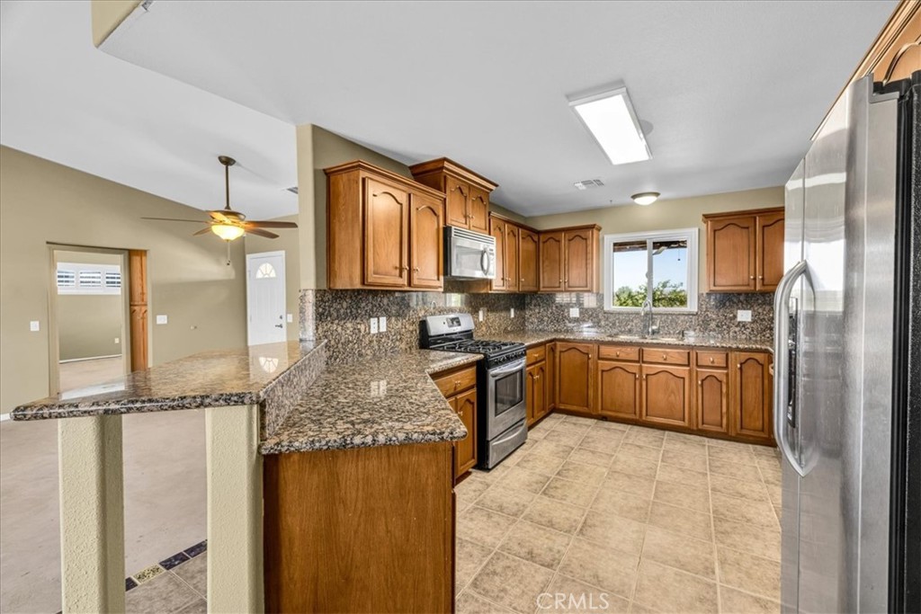 63357 Uranium Road Joshua Tree, CA 92252 - Photo 7 of 54 a kitchen with kitchen island granite countertop wooden cabinets and a refrigerator