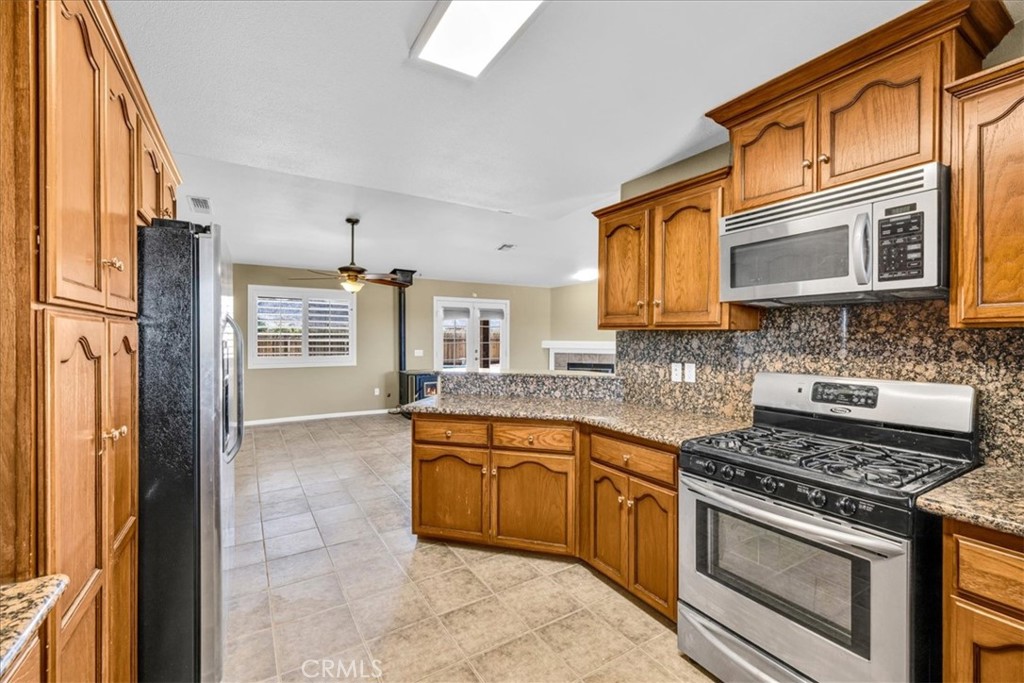 63357 Uranium Road Joshua Tree, CA 92252 - Photo 8 of 54 a kitchen with stainless steel appliances granite countertop a stove top oven a refrigerator and a granite counter tops with white cabinets