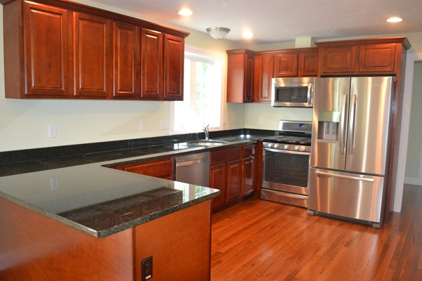4 Waxen Way Shirley, MA 01464 - Photo 8 of 12 a kitchen with stainless steel appliances granite countertop a refrigerator a sink dishwasher and wooden cabinets with wooden floor