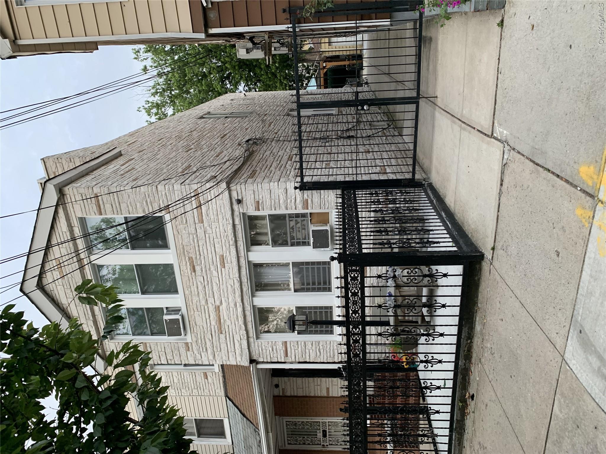 97-21 83rd Street Queens, NY 11416 - Photo 8 of 8 View of front of property with stone siding, a gate, a fenced front yard, and cooling unit