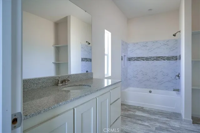 a bathroom with a granite countertop sink a mirror and a bathtub