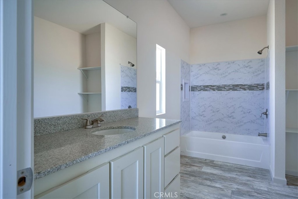 13358 Buttonwood Street Phelan, CA 92371 - Photo 22 of 33 a bathroom with a granite countertop sink a mirror and a bathtub