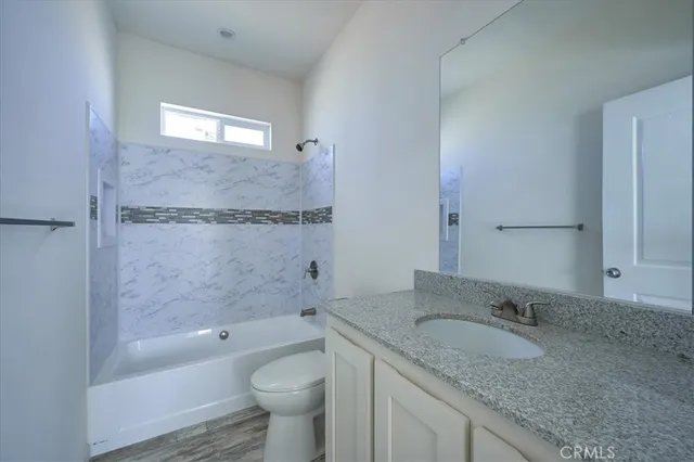 a bathroom with a granite countertop sink a toilet and bathtub