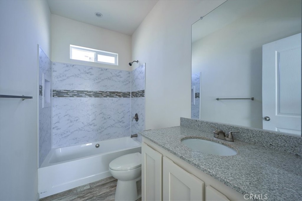 13358 Buttonwood Street Phelan, CA 92371 - Photo 31 of 33 a bathroom with a granite countertop sink a toilet and bathtub