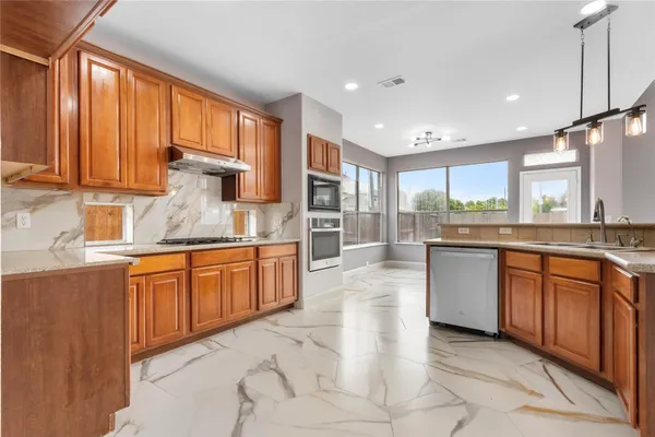 a large kitchen with stainless steel appliances granite countertop wooden cabinets a granite counter tops and a large window