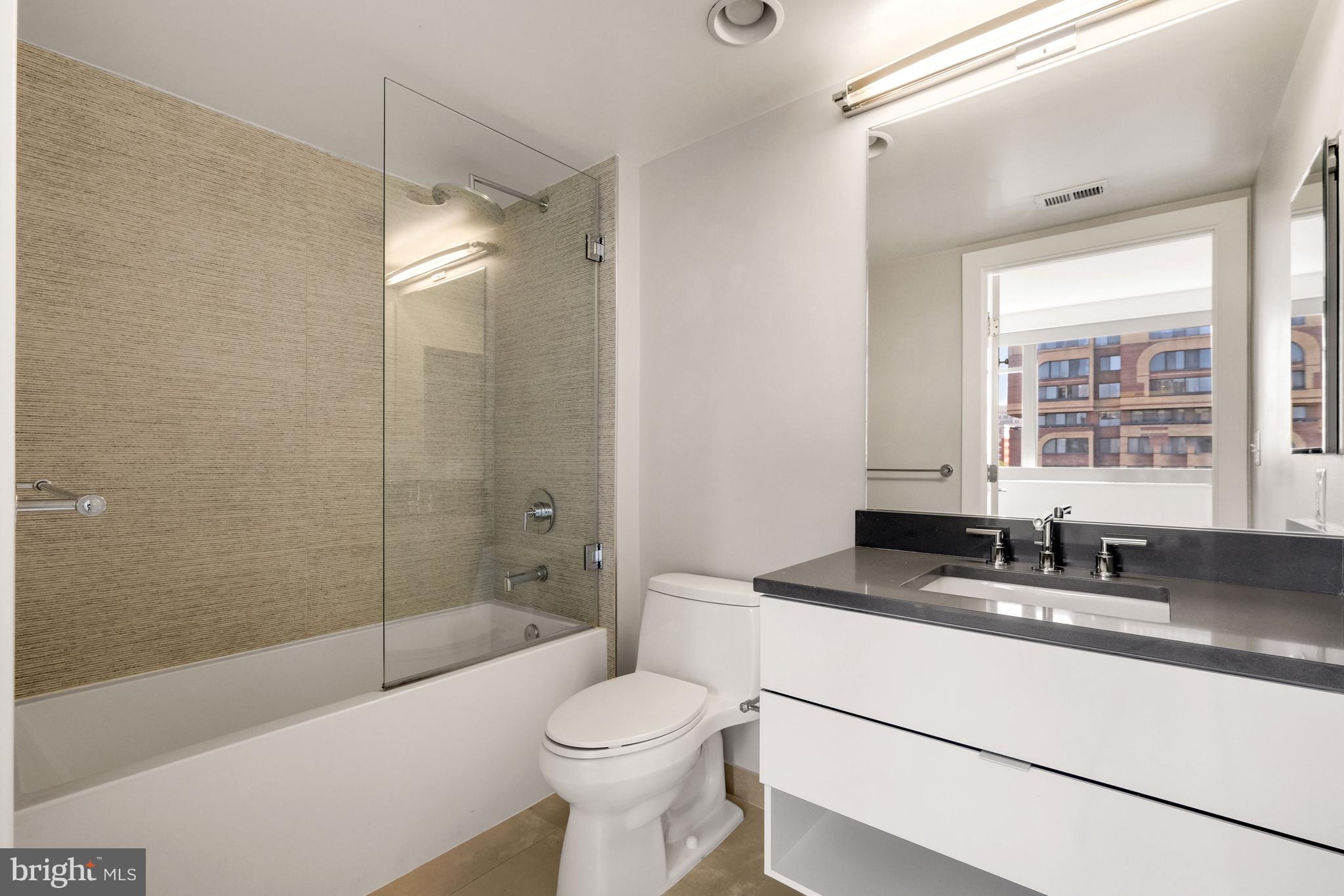 1311 13th Street Northwest, Unit 409 Washington, DC 20005 - Photo 19 of 25 a bathroom with a granite countertop sink a toilet a bathtub and shower