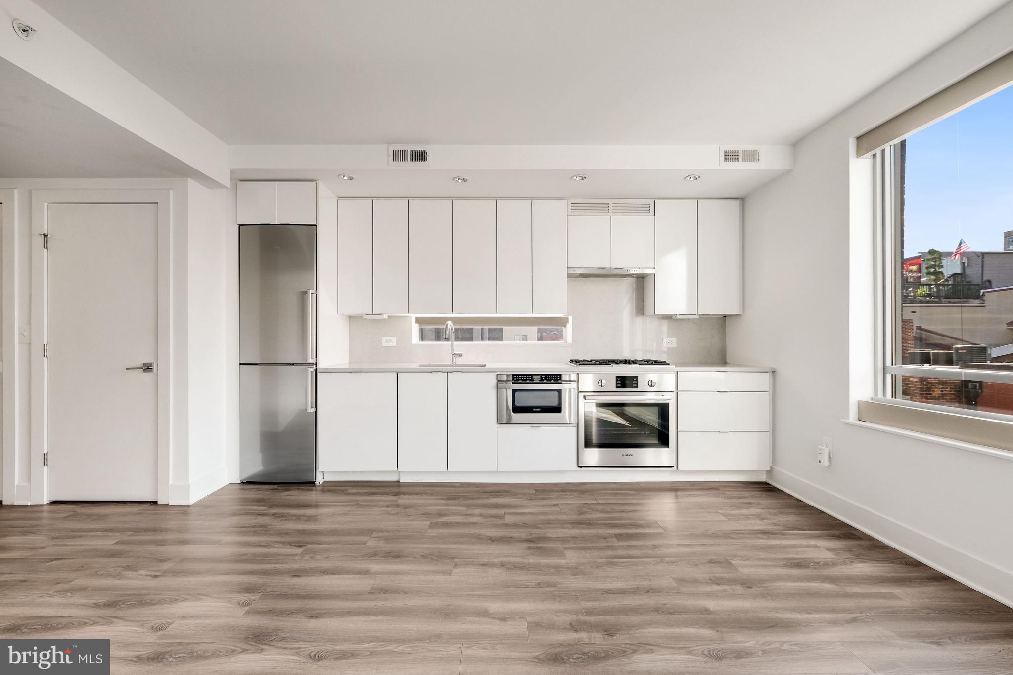 1311 13th Street Northwest, Unit 409 Washington, DC 20005 - Photo 8 of 25 a kitchen with granite countertop white cabinets and stainless steel appliances
