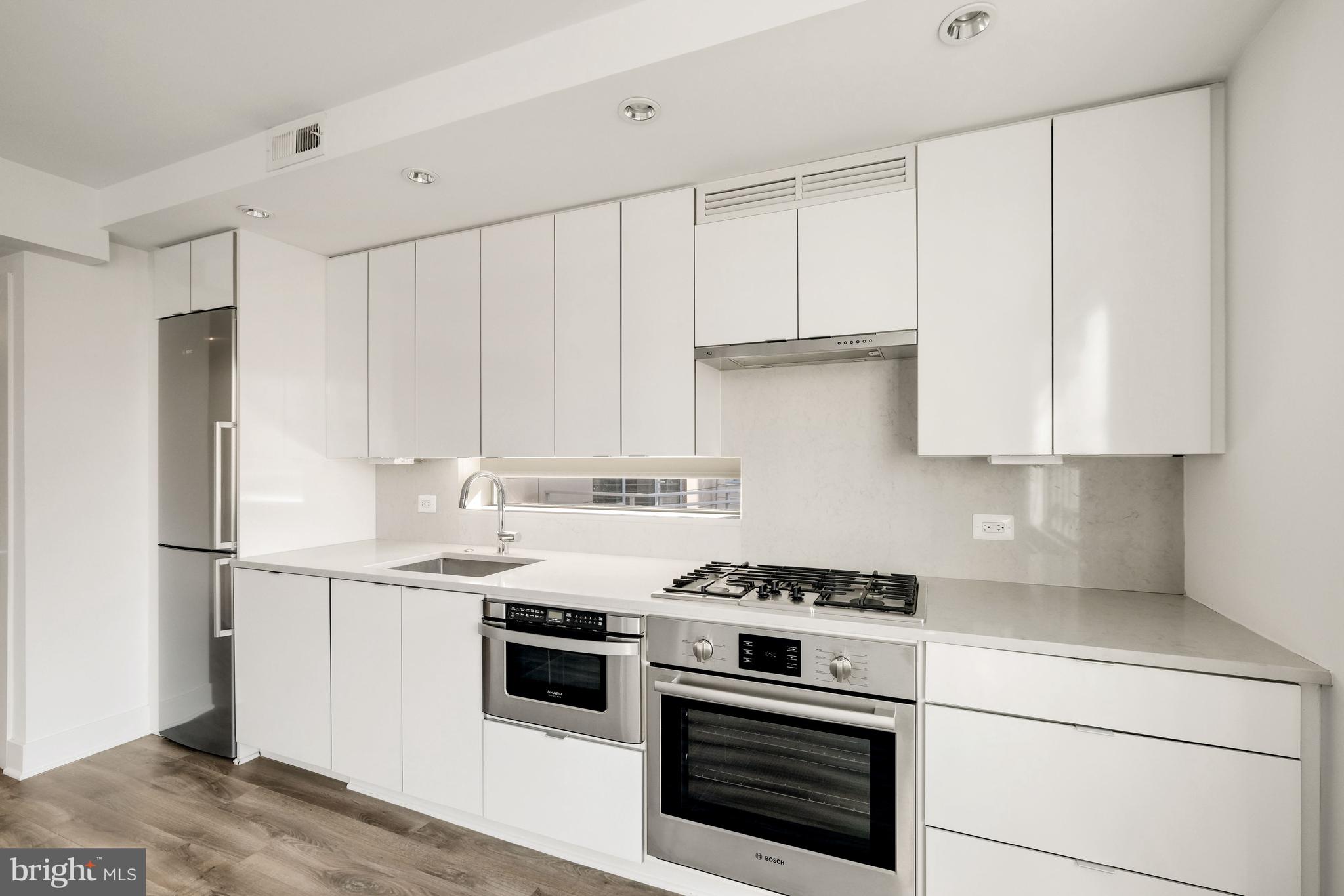 1311 13th Street Northwest, Unit 409 Washington, DC 20005 - Photo 10 of 25 a kitchen with granite countertop white cabinets and white appliances