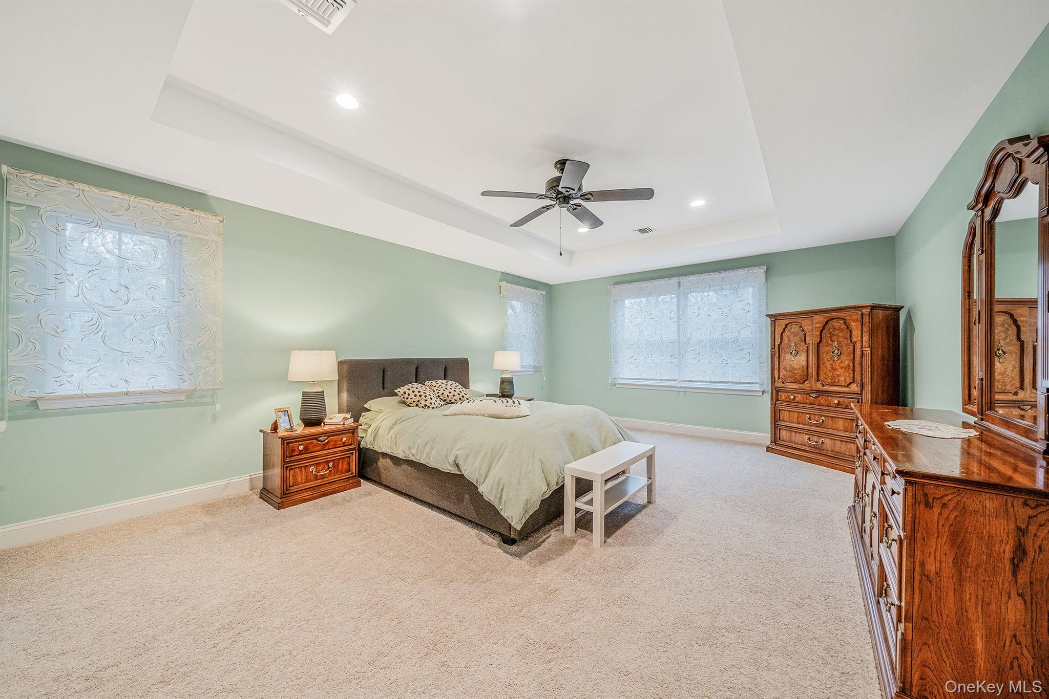 152 Wood Road Centereach, NY 11720 - Photo 18 of 35 a spacious bedroom with a bed and a chandelier