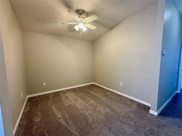 an empty room with windows and chandelier fan