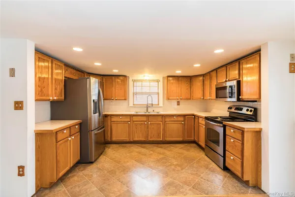 a large kitchen with stainless steel appliances granite countertop a stove a sink dishwasher and a refrigerator