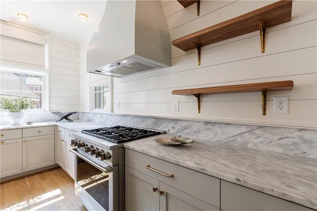 a kitchen with granite countertop stainless steel appliances a sink a stove and a window