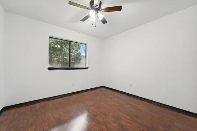 an empty room with a window and a ceiling fan