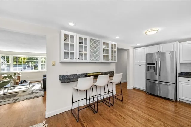 a kitchen with stainless steel appliances granite countertop a dining table chairs refrigerator and sink