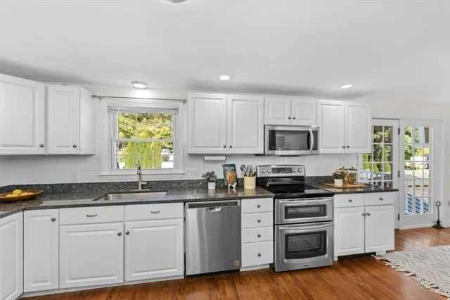 a kitchen with granite countertop white cabinets and stainless steel appliances