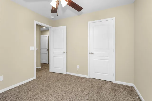 an empty room with closet and a chandelier fan