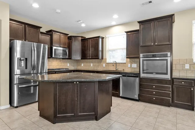 a kitchen with kitchen island granite countertop stainless steel appliances and cabinets