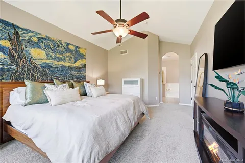 a spacious bedroom with a bed and a flat screen tv