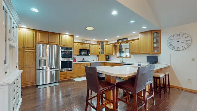 a kitchen with stainless steel appliances granite countertop a dining table chairs refrigerator and a sink