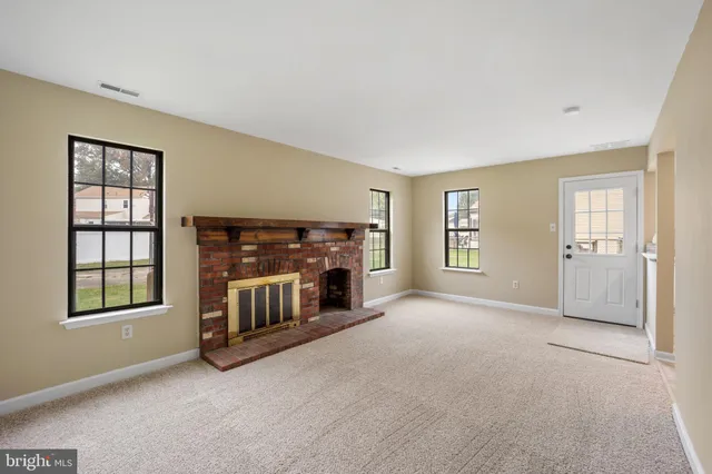 a view of an empty room with a fireplace and a window