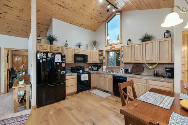 a kitchen with stainless steel appliances kitchen island granite countertop a refrigerator a stove a sink dishwasher and white cabinets with wooden floor