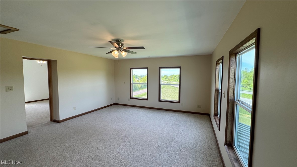 6255 Highland Ridge Road Lowell, OH 45744 - Photo 14 of 40 Empty room featuring light carpet, baseboards, and a ceiling fan