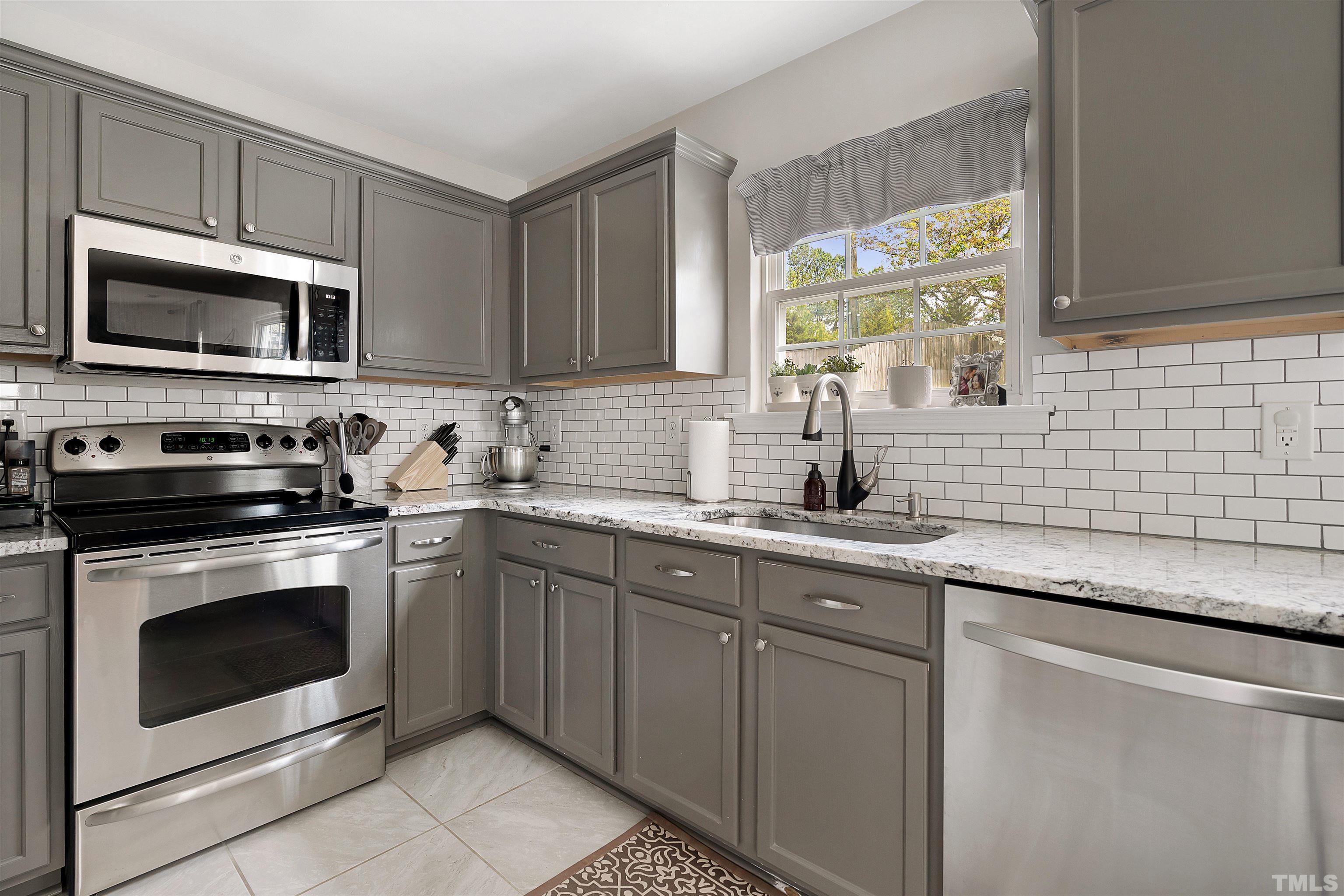 12440 North Exeter Way Durham, NC 27703 - Photo 17 of 36 a kitchen with stainless steel appliances granite countertop grey cabinets a stove a sink and a microwave