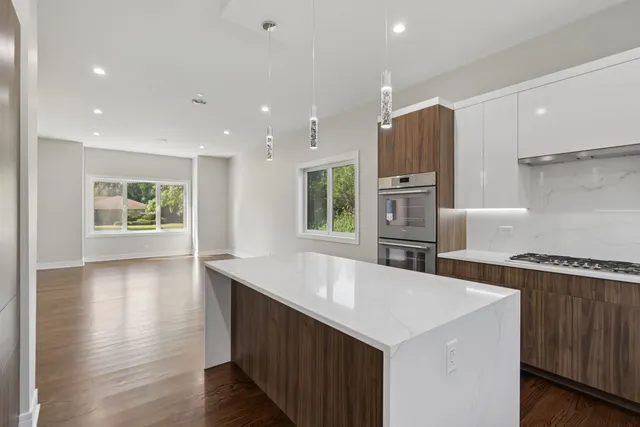 a kitchen with a center island wooden floor and stainless steel appliances