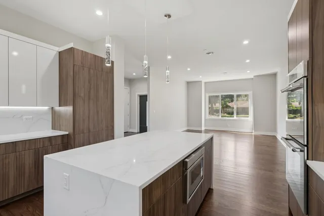 a kitchen with stainless steel appliances a kitchen island a stove a refrigerator and a sink with wooden floor