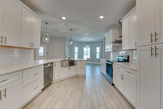 a large kitchen with cabinets wooden floor and stainless steel appliances