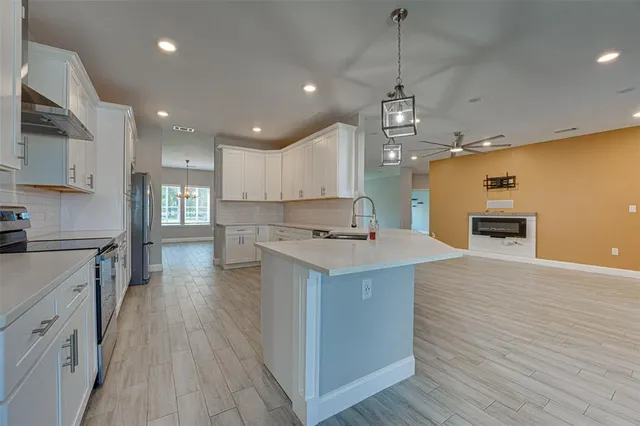 a kitchen with kitchen island a stove a sink a center island and wooden floor