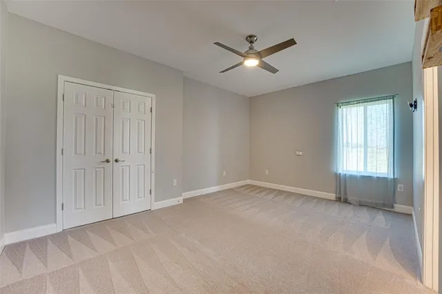 a view of an empty room with chandelier fan